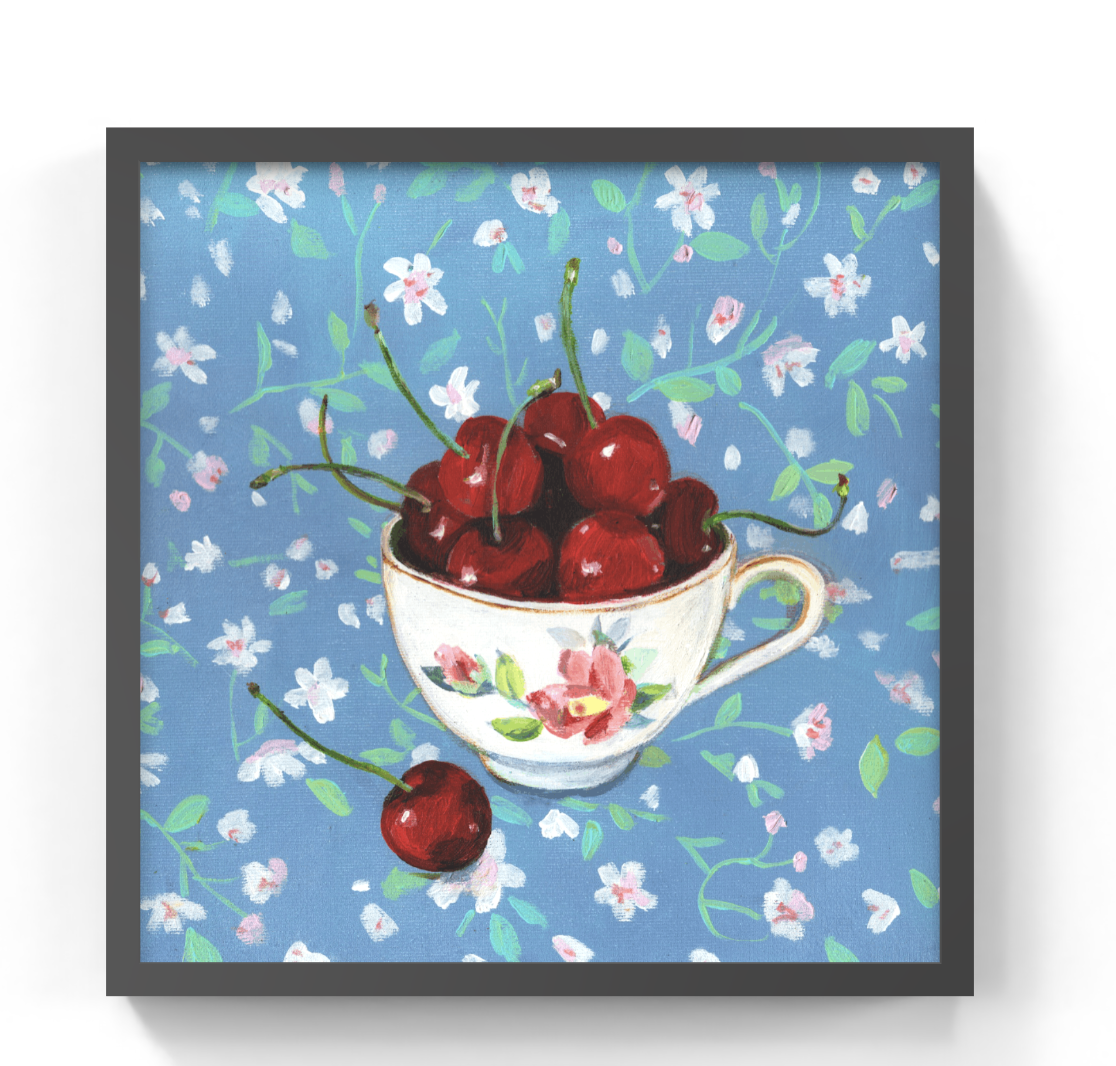 Framed square wall art featuring a painted still life of red cherries in a floral teacup against a blue floral background, shown with a dark frame on a white wall.