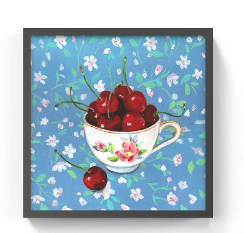 Framed square wall art featuring a painted still life of red cherries in a floral teacup against a blue floral background, shown with a dark frame on a white wall.