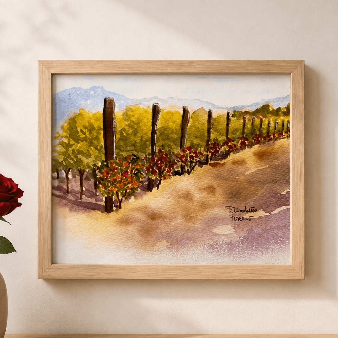 Framed painting of a vineyard with a red rose in a vase on a wooden surface.